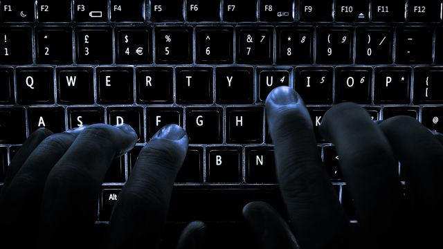 A backlit laptop computer keyboard. Most fingers are on the "home" keys for touch-typing; the 'U' key is being pressed.