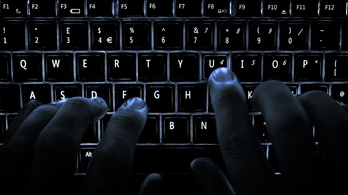 A backlit laptop computer keyboard. Most fingers are on the "home" keys for touch-typing; the 'U' key is being pressed.